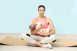 © Pixel-Shot - Beautiful young sporty woman with her little baby meditating near blue wall