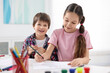 © New Africa - Happy brother and sister drawing at white table in room