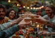 © Lucianastudio - Friends toast with drinks in their hands, with a festive outdoor barbeque scene and string lights overhead. The background captures the lively atmosphere without revealing any faces.