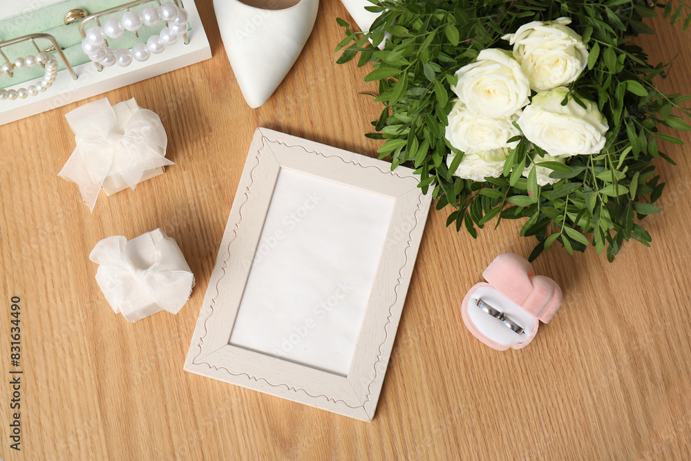 Wedding composition with bridal bouquet, photo frame and ring boxes on wooden background