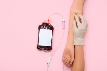 Wall Mural - Female hands with blood pack for transfusion on pink background