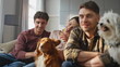 © stockbusters - Pet owners relaxing couch watching tv together close up. Friends caressing dogs