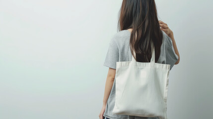 Young girl in urban setting holding a white cotton tote bag against white wall