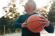 © Nano - Adult male athlete about 50 years old, practicing basketball in a wheelchair, with a disability, and wearing sports clothing. with detail in the hands and ball, in a park and sunny day