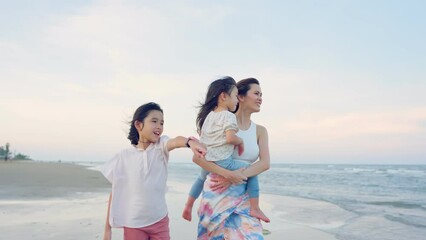 Wall Mural - Asian mother and daughters walking on the beach during summer together. 