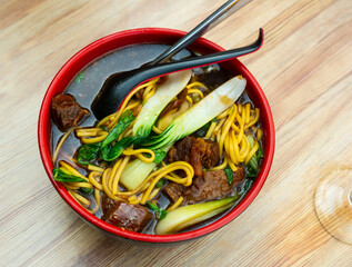 Sticker - Chinese beef soup with noodles and green mustard cabbage served in a bowl