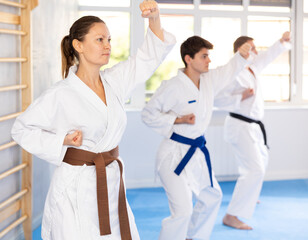 Three athletes have taken starting position and studying and repeating sequence of punches and painful techniques in karate kata technique. Oriental martial arts, training and obtaining black belt