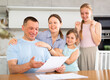 © JackF - Happy family receiving written notification of positive decision from bank or credit organization about approval of loan or mortgage. Cheerful man with wife and teenage daughters reading some papers