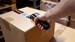 © Hanasta - Close up of hand using bar code scanner to scan on cardboard box with damaged label in warehouse