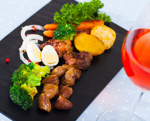 Wall Mural - Appetizing braised chicken hearts with vegetable garnish of baked potatoes, broccoli, carrots and quail eggs