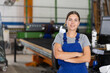 © JackF - Confident smiling young female worker posing with crossed arms in glass factory, against blurred background of workshop setting, showcasing professionalism and pride in job