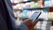 © Thanthara - Customer reviewing a medication app on a smartphone in a pharmacy, close-up, screen glow