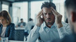 © VK Studio - Frustrated businessman with headache during a stressful meeting at the office.