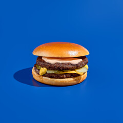 massive double-patty burger on a blue background, boasting juicy meat and bold flavors. modern minim