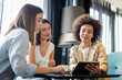 © NDABCREATIVITY - Business woman and her clients discuss business ideas and collaborate over coffee in a cafe.