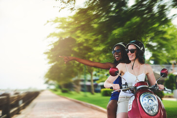 Poster - Travel, scooter and women with helmet pointing for adventure, summer vacation or sightseeing. Outdoor, holiday and happy friends with sunglasses for transportation, explore or road trip to India