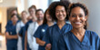 © nopommajun - A cheerful female healthcare worker is in focus, with her medical team blurred in the background
