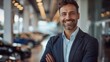 © Attasit - Portrait of smile handsome Salesman Standing Standing and hugging tablet on chest looking at camera in a modern car showroom