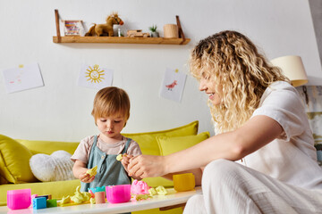 Wall Mural - A curly mother and her toddler daughter engage in playful learning using the Montessori method of education at home.