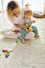 Wall Mural - Curly mother and toddler daughter bond over Montessori block play, creating, stacking, and exploring together on the floor.