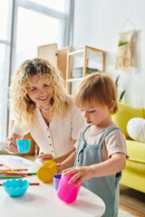 Wall Mural - A curly mother and her toddler daughter engage in playful Montessori cup activities at home.