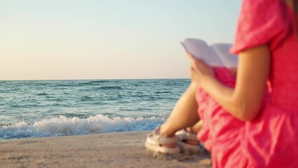 Wall Mural - Woman reading book at beach on sunny morning, closeup. Focus on sea waves rolling on sand