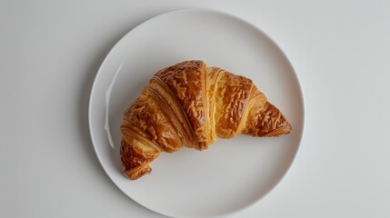 Wall Mural - French croissant photographed from a top down perspective on a white plate and backdrop