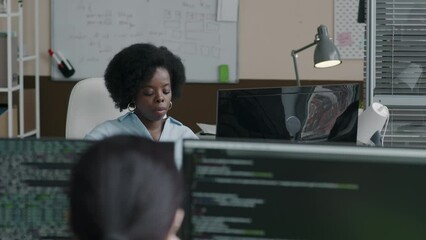 Wall Mural - young black woman using desktop computer while working in minimalist style office with female collea