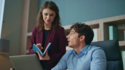 Wall Mural - Woman mentor checking work man trainee in corporate office. Couple colleagues