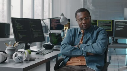 Wall Mural - medium slowmo portrait of young confident african american system administrator sitting in office ch