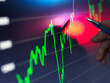 © Connect Images - A hand holding a pen points to a bright stock market chart on a digital screen with fluctuating green and red graph lines indicating financial data.