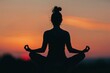 © Mike - A silhouette of a woman meditating in the lotus position, capturing a serene and tranquil moment