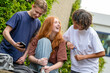 © Connect Images - Three teenagers are laughing together outdoors, with one holding a smartphone.