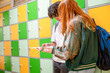© Connect Images - Two teenagers are standing by a row of colorful school lockers, looking at a book one of them is holding.