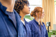 © Connect Images - Three individuals dressed in blue uniforms are standing side by side, with the focus on the middle person who appears to be looking thoughtfully towards the left.