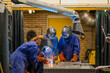 © Connect Images - Three individuals are welding metal components in an industrial environment, wearing protective gear including welding helmets and gloves.