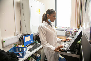 Female technician operating advanced machinery in a medical practice, UK