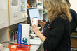 © Connect Images - Pharmacist examining a medication bottle at a workspace.