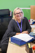 © Connect Images - Smiling woman sitting at a desk with papers and office supplies in a medical practice