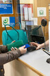 © Connect Images - A person making a payment at a reception desk of a hospital