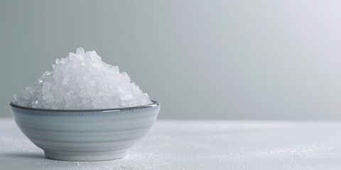 Bowl of white crystals on pale surface, minimalist design