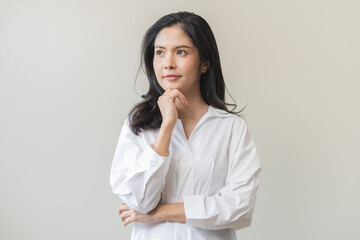 Poster - Portrait of positive thoughtful asian young woman, girl keeps hand on chin looking away in white shirt casual, adult female thinking creative, thinks about future person, isolated on white background.