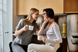 © Bliss - A young lesbian couple enjoying coffee together in a hotel kitchen.