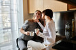 © Bliss - Two women in a hotel kitchen, sipping coffee together, showcasing love and unity.
