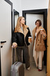 © Bliss - A young lesbian couple stands in a hotel hallway with luggage, ready to embark on a new journey together.