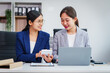 © NanSan - Two Asian businesswomen collaborate on stock market strategies and financial services, exchanging comments and suggestions on loan applications and investment opportunities.