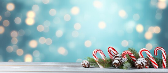 Wall Mural - Beautiful Christmas composition with candy canes fir tree branches and space for text on light blue wooden table flat lay Bokeh effect. copy space available