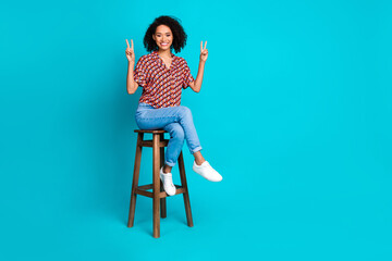 Sticker - Photo of positive girl sit chair make v sign isolated cyan color background