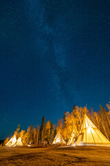 Wall Mural - Amazing starry night sky and milky way galaxy over the light up Tipi or Tepees. Yellowknife, Northwest Territories, Canada.