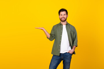 Poster - Photo of nice young man hold empty space wear khaki shirt isolated on yellow color background